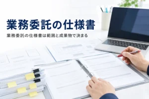 業務委託の仕様書の書き方を紹介する記事のアイキャッチ。机に広げた仕様書と付箋の貼られた書類